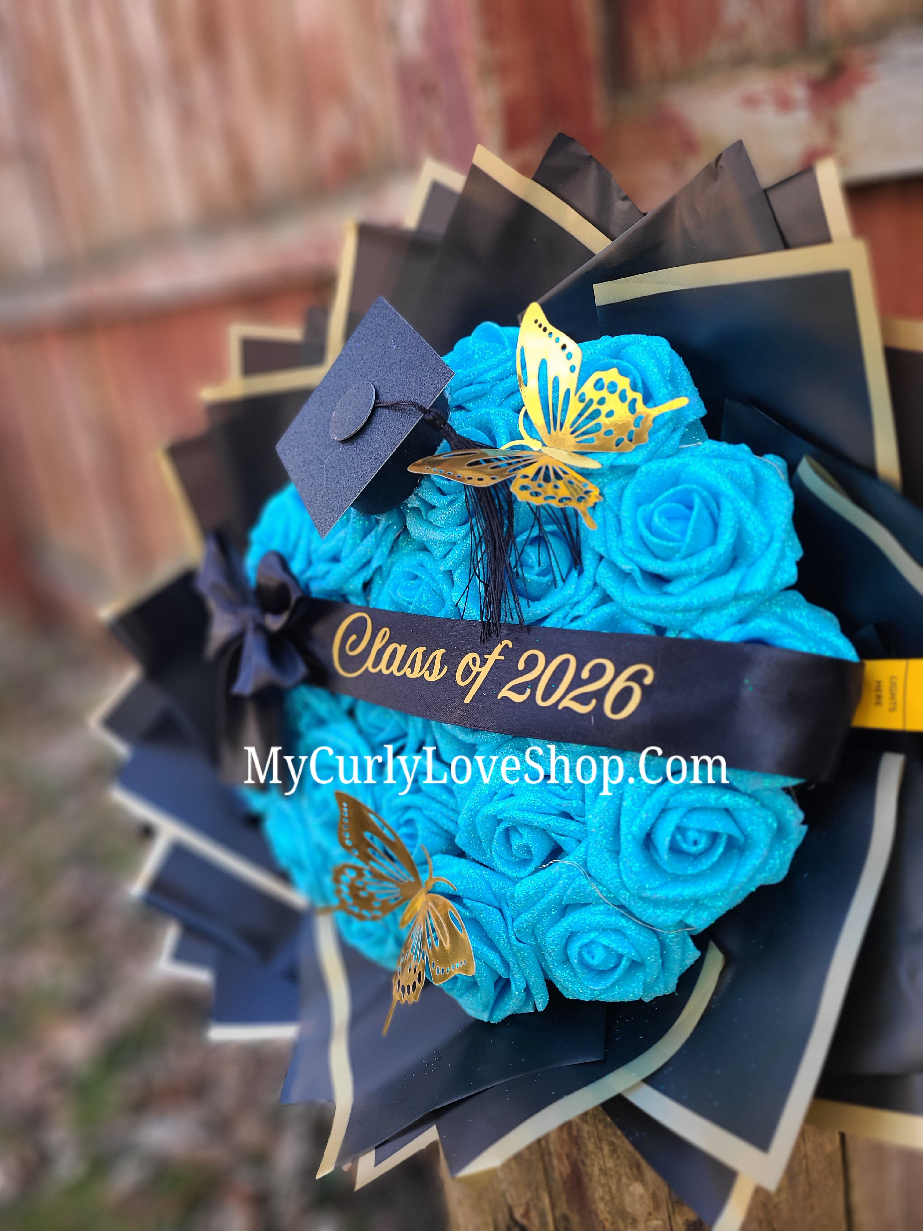 Graduation Glitter Roses Bouquet. Graduation Cap and 2 gold butterflies Included. Banner and Lights are additional.