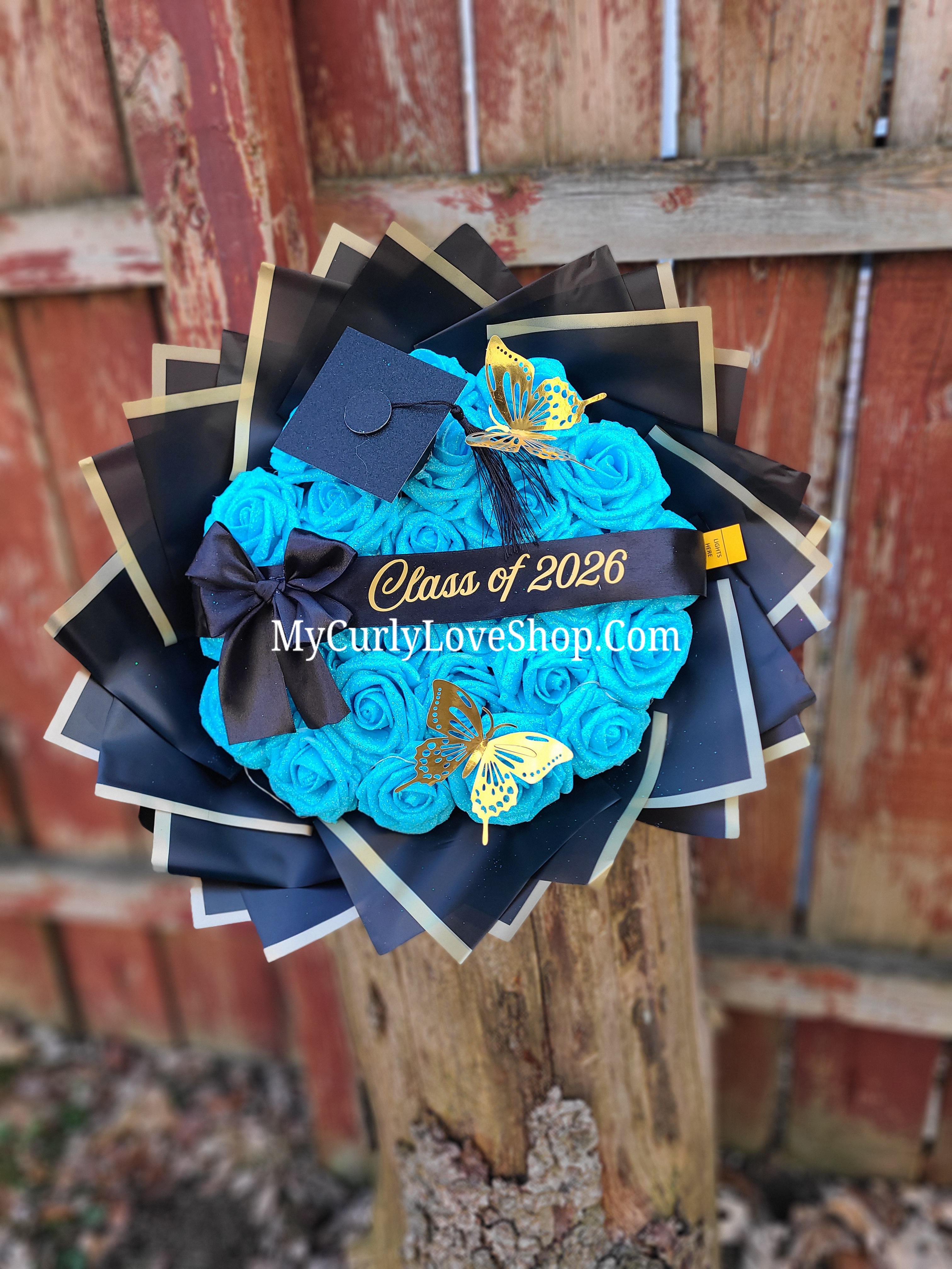 Graduation Glitter Roses Bouquet. Graduation Cap and 2 gold butterflies Included. Banner and Lights are additional.