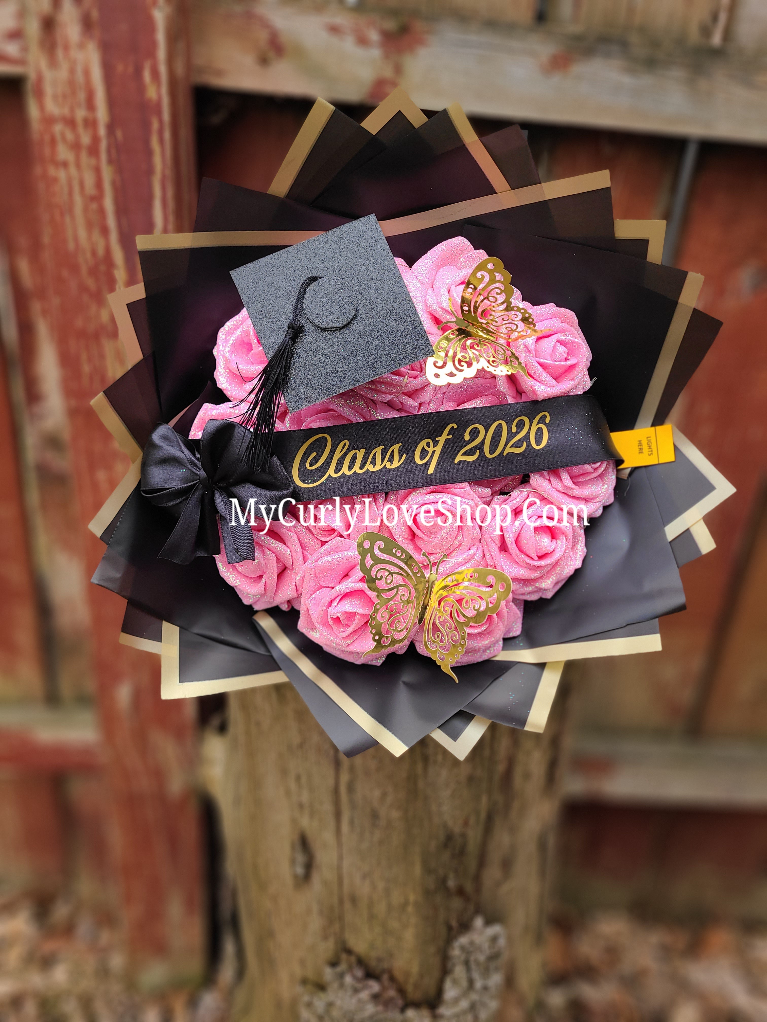 Graduation Glitter Roses Bouquet. Graduation Cap and 2 gold butterflies Included. Banner and Lights are additional.