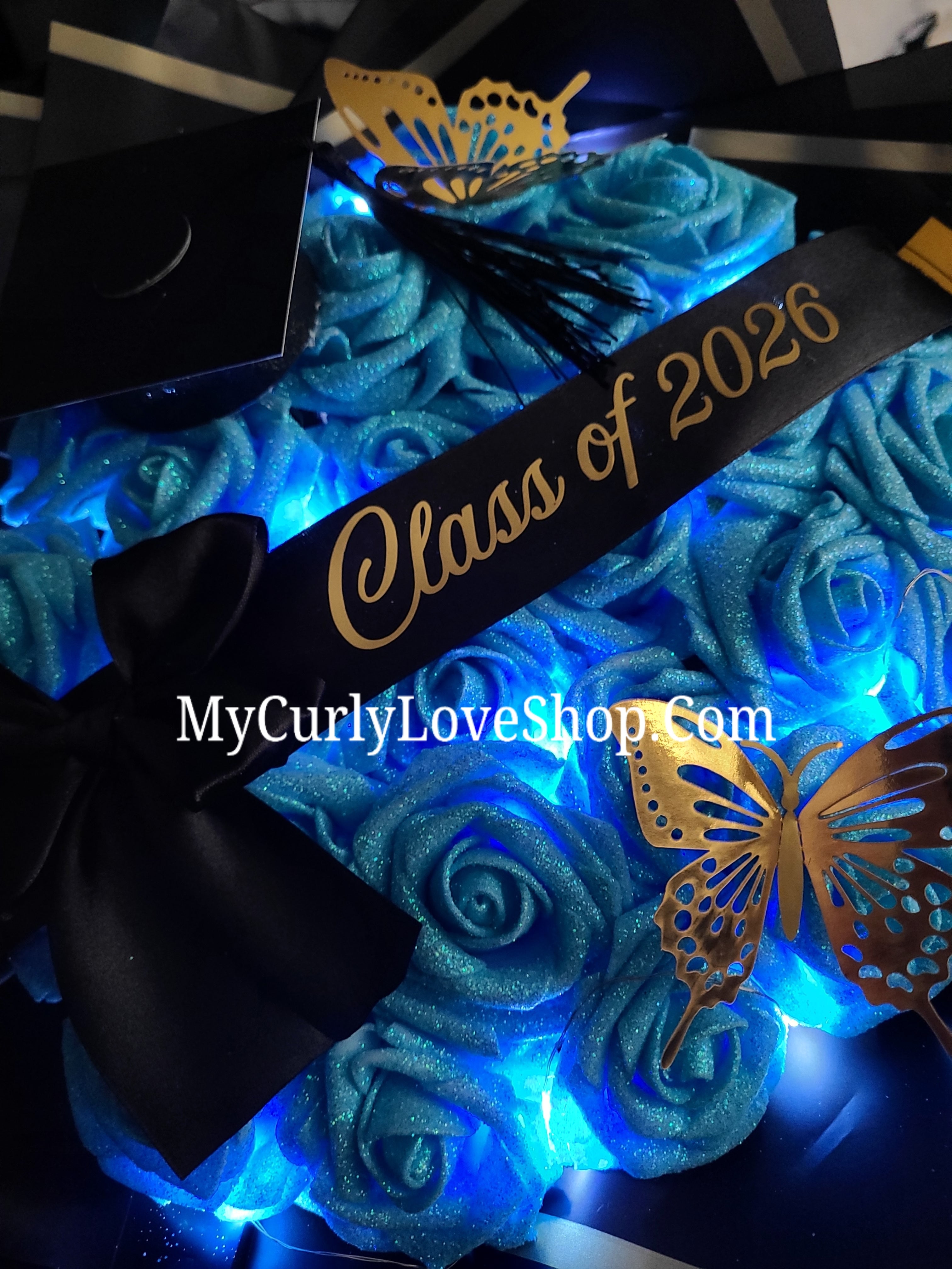 Graduation Glitter Roses Bouquet. Graduation Cap and 2 gold butterflies Included. Banner and Lights are additional.